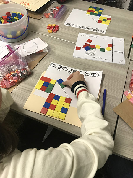 A person puts colored squares on a Pythagorean Theorem worksheet