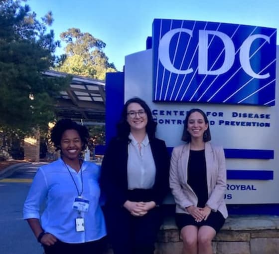 3 AU health students smiling at CDC entrance.