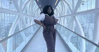 Oreoluwa Erinfolami on an elevated glass and metal catwalk in a modern building