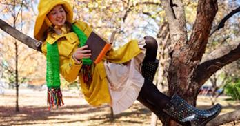 A character from Sometimes the Rain, Sometimes the Sea wearing a yellow raincoat and rain hat, green scarf, pink dress and multicolored rainboots