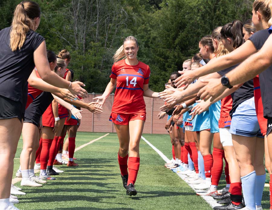 Brooke Steel runs between rows of teammates, giving high fives