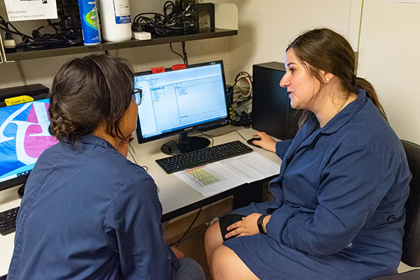 Two lab workers look at data on the computer