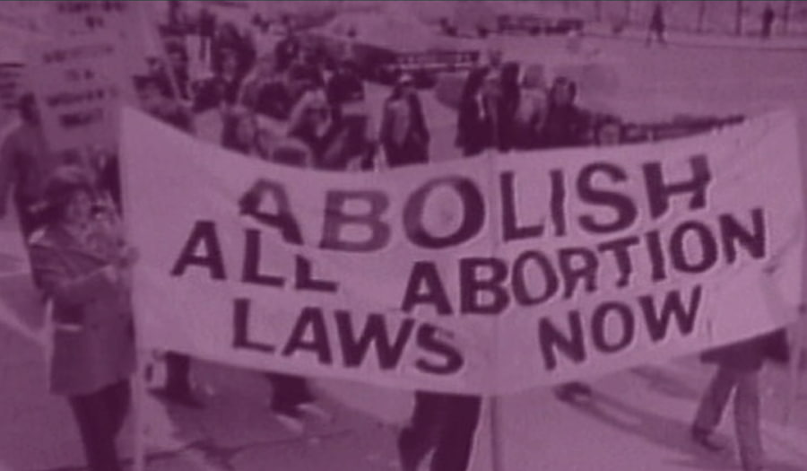 Protestors carrying signs and banner that reads, abolish all abortion laws now