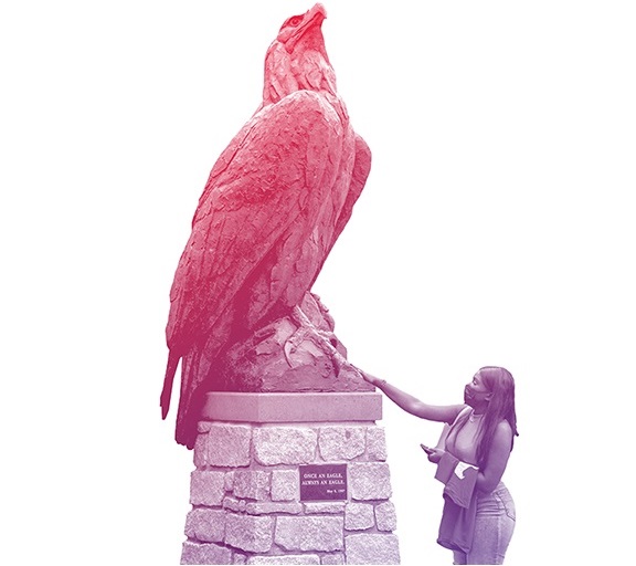 A student touching the bronze eagle statue at convocation