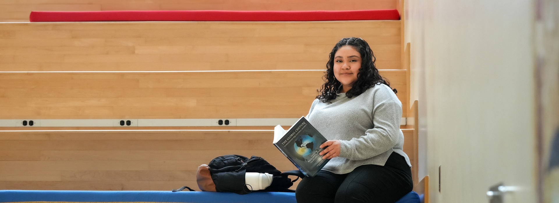 Rosy Chavez-Martinez sits reading on the steps in the School of International Service atrium at American University.