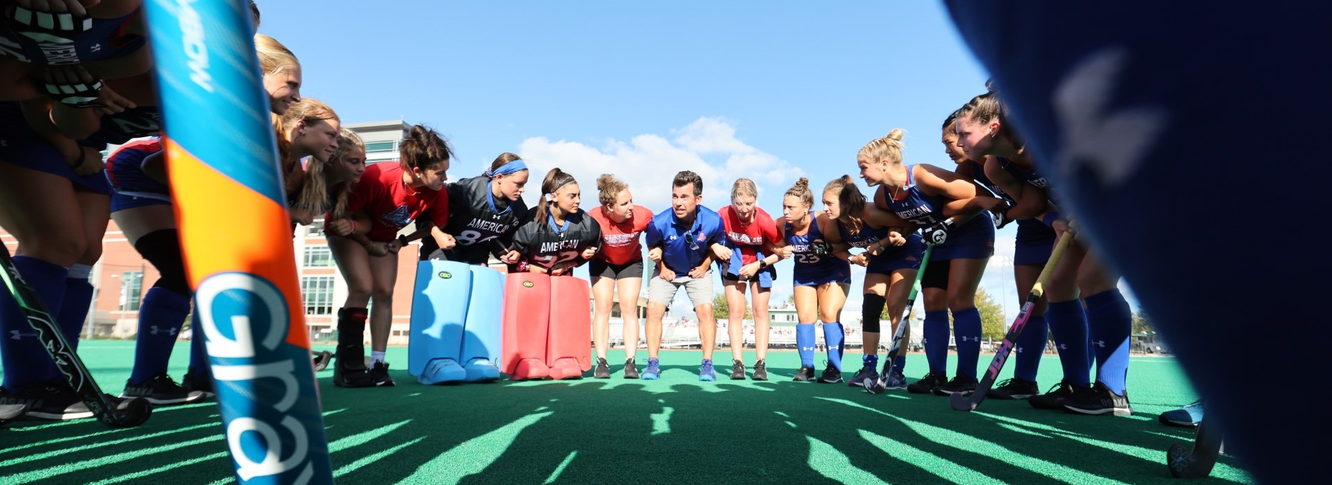 AU Field Hockey team gathered in a huddle with Coach Jennings.