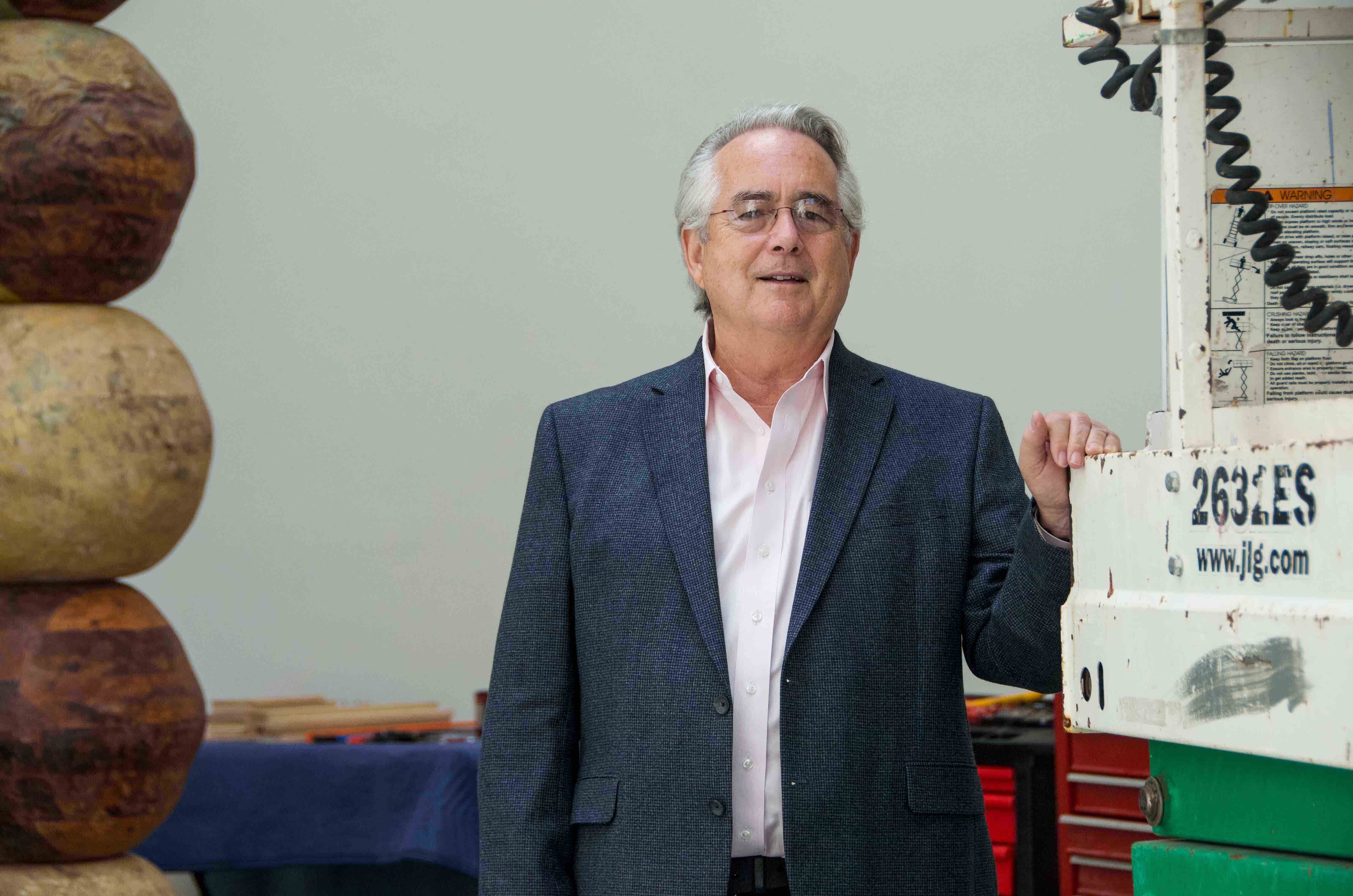 Jack Rasmussen stands next to forklift installing a sculpture in AU Museum.