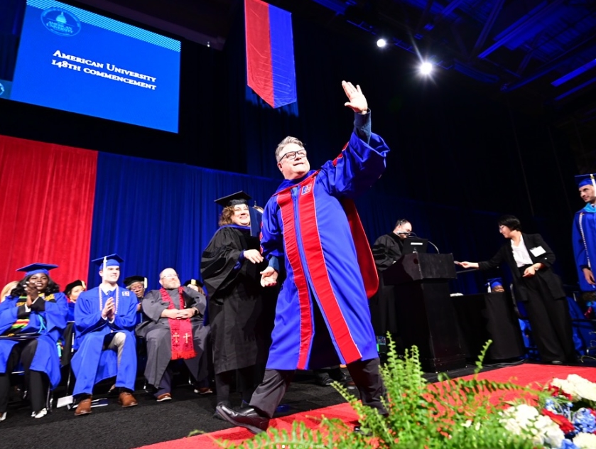 Sean Astin walks across the stage at commencement.