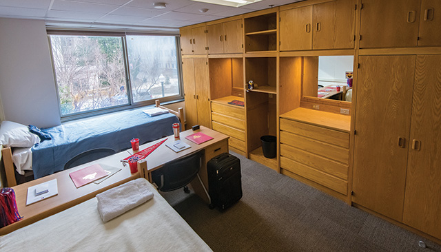 Campus housing room with linens and luggage