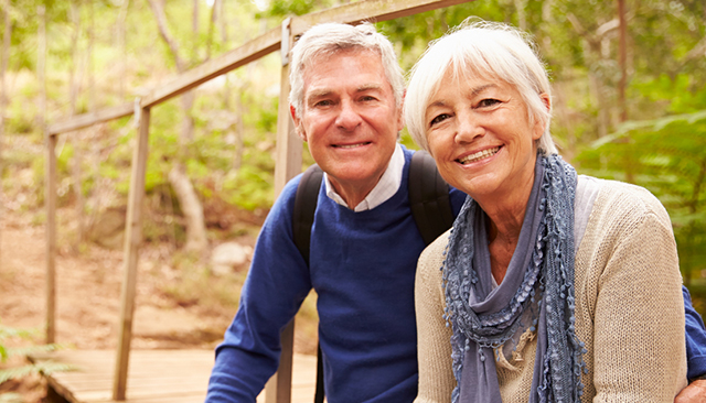 Happy senior couple sitting on a bridge in a forest