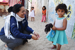 Valerie Guarnieri kneels next to a child