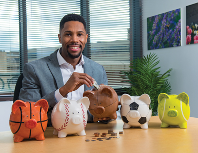 Romone Penny inserts money into a piggy bank shaped like a football.