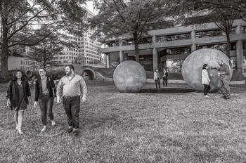 Seven AU alumni stand near a fountain in Dark Star Park in Rosslyn