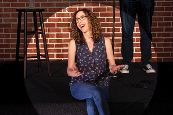 Allyson Jaffe sits and laughs on the DC Improv stage