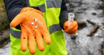 A close-up of a female scientist holding up a collection of small plastics she has found whilst collecting samples of water.
Credit: Getty Images