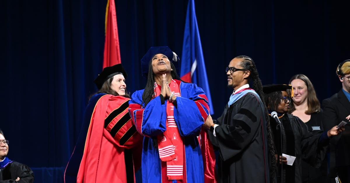 An AU School of Education graduate lifts their head to the sky. Photo by Jeff Watts. 