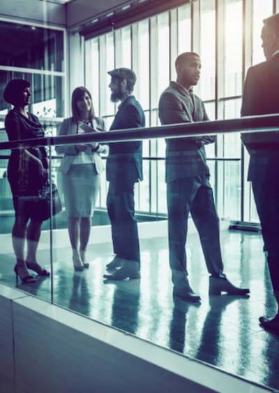 People in conferring in walkway of a modern building.