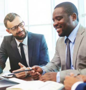 Divere people in professional dress smiling in a sit-down meeting.