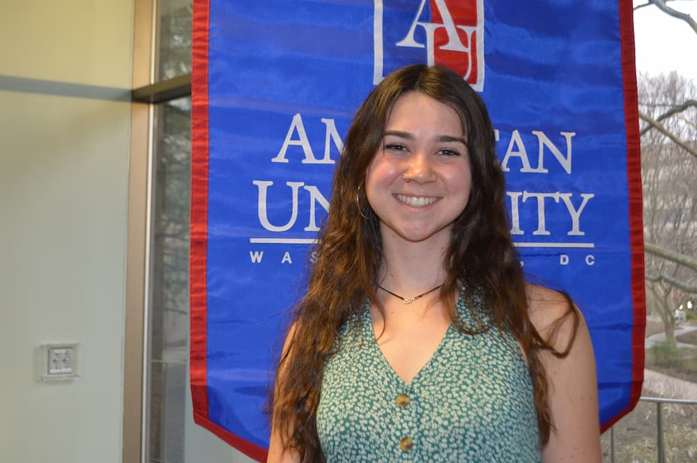 Ashley Hocking standing in front of AU banner