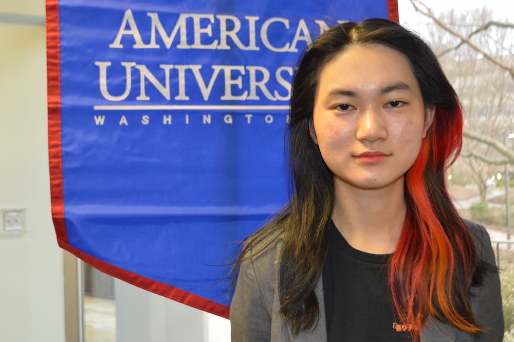 Catherine Hou standing in front of AU banner