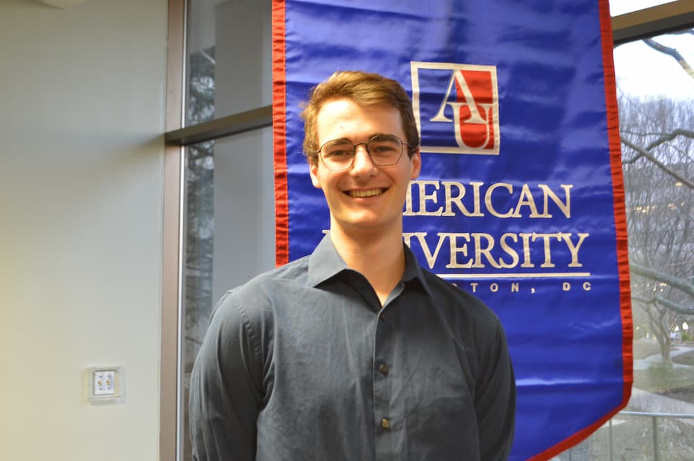 Collin Coil standing in front of AU banner