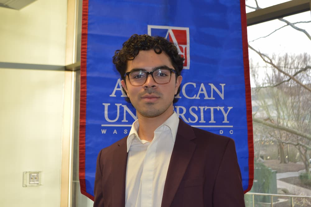 John Paul Mejia standing in front of AU banner