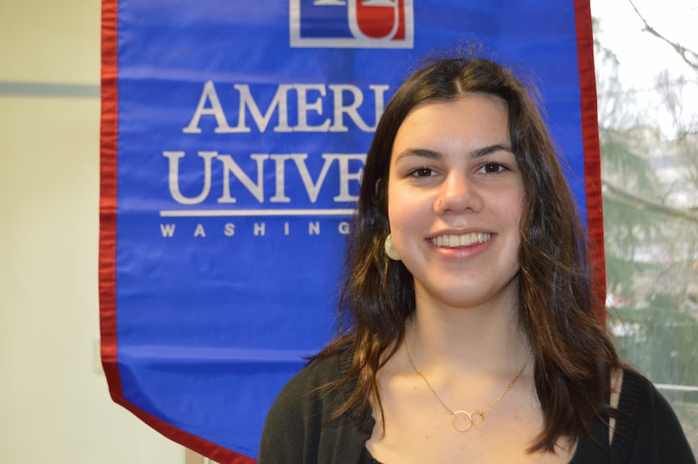 Maddie Young standing in front of AU banner