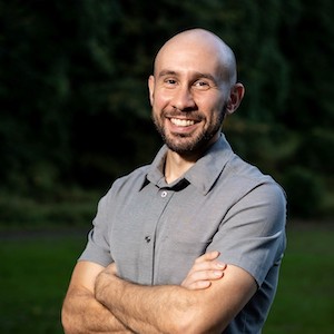 Person wearing gray shirt standing outside with arms crossed