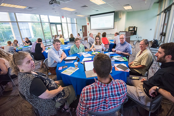 Photo of AU Core faculty talking with one another at round tables.