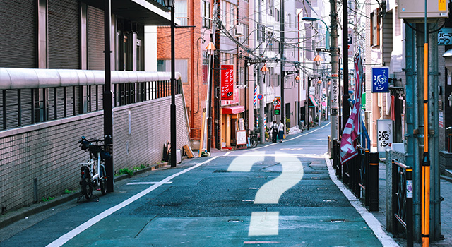 question mark on an empty road with Japanese store signs on both sides