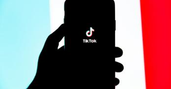 A phone screen displays the words "TikTok"