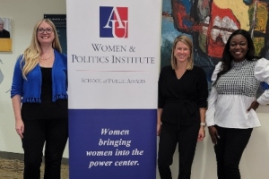 three welead alumni standing next to banner