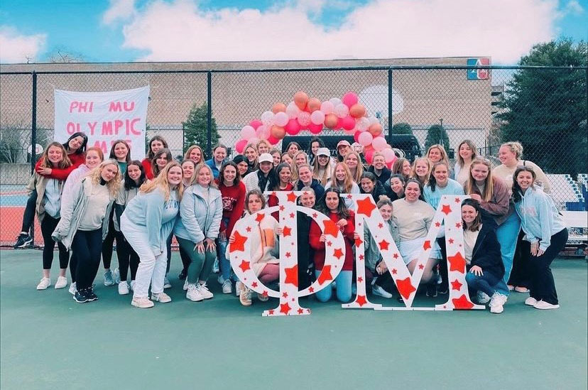 A group of sorority students gather outside with Greek letters.