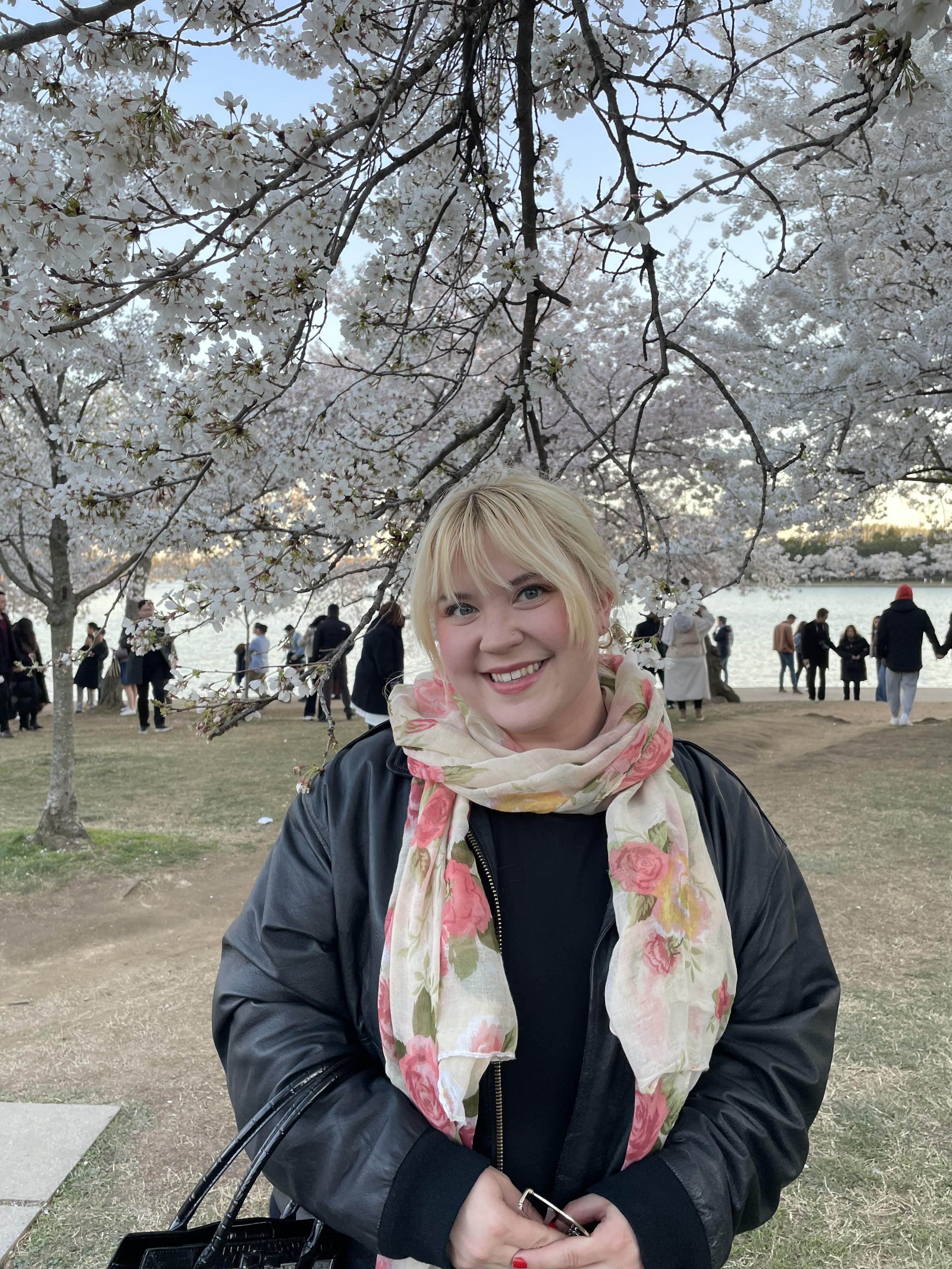 Headshot of Madeline Brown standing in front of cherry blossoms.