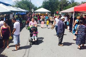 People at a farmers' market, woman with stroller.