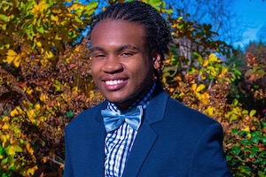 Photo of Jjayi in navy jacket and bowtie.