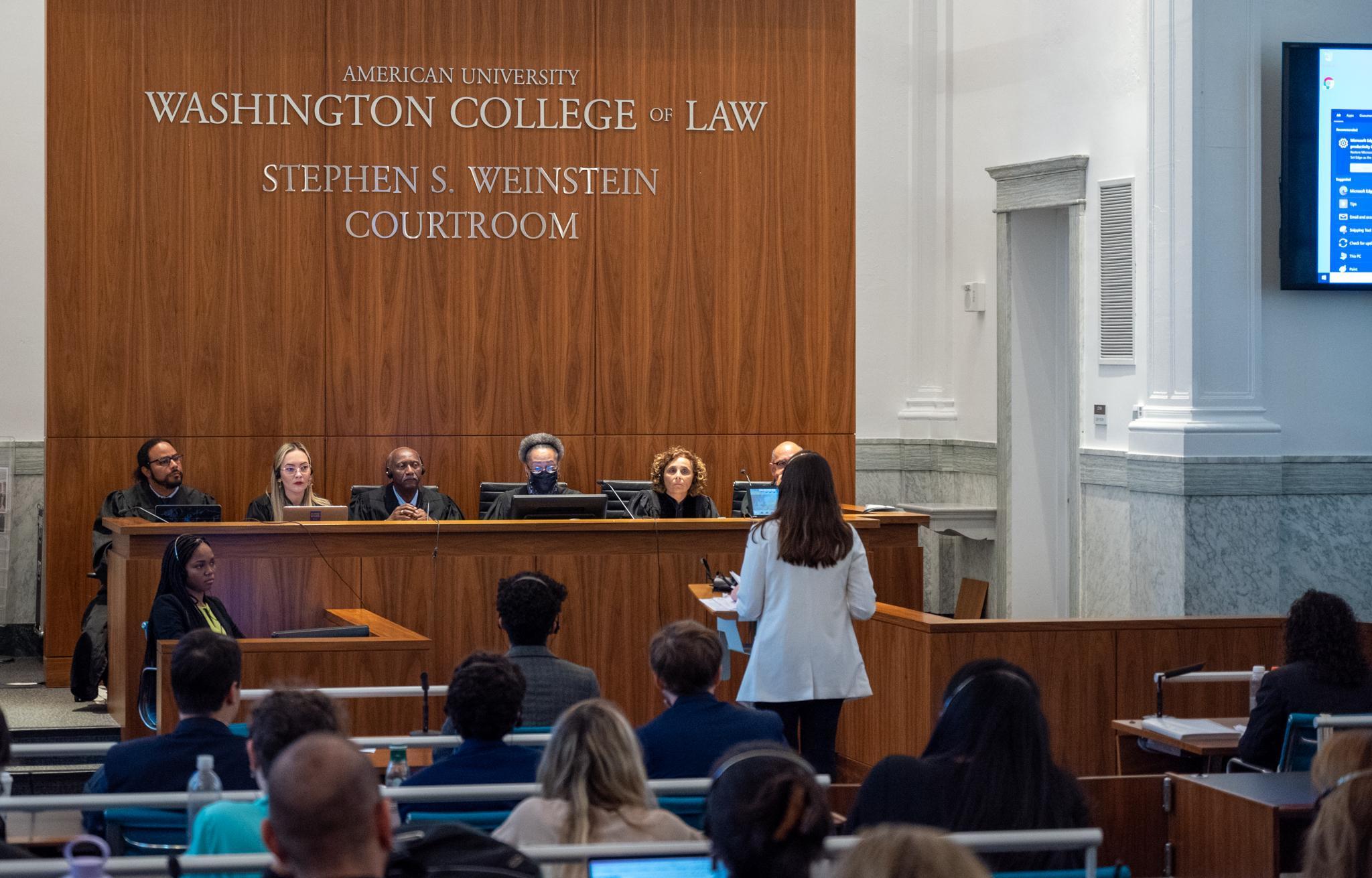 Judges and students listen as a participant argues their case.